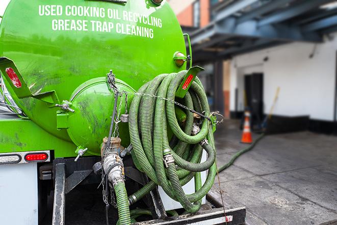 a professional plumber using a pump to empty a grease trap in Attleboro