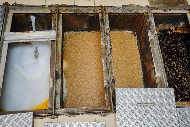 a commercial kitchen grease trap getting a thorough cleaning